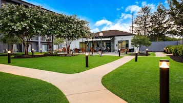 A hotel courtyard with a paved walkway, seating areas, and a building entrance.