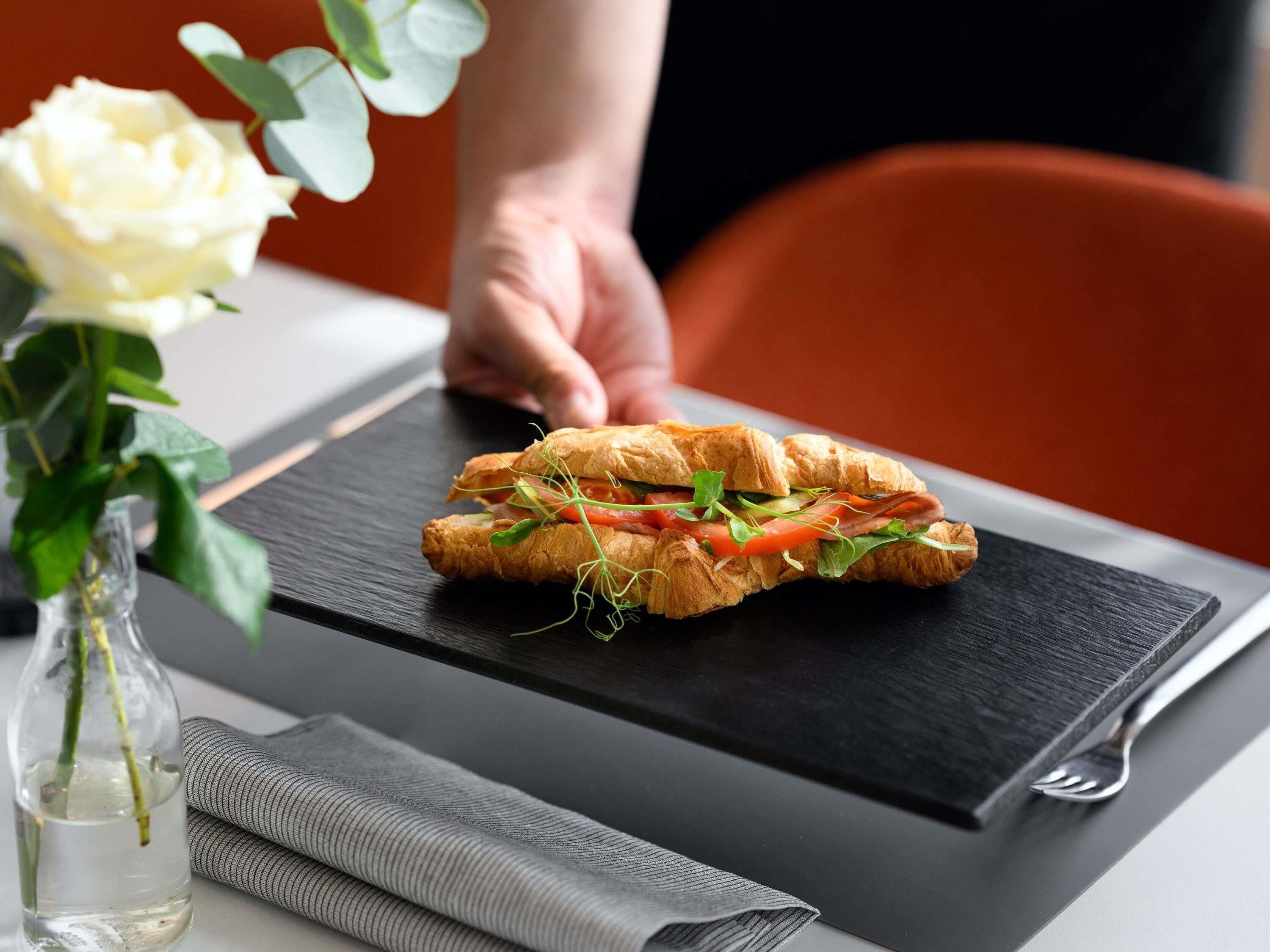 A sandwich on a slate plate with a folded napkin and a fork beside it.