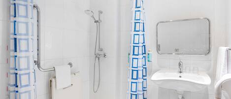A bathroom with a shower, a sink, a mirror, and a towel rack.