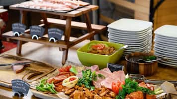 A buffet with various meats, vegetables, and a green bowl of salad.
