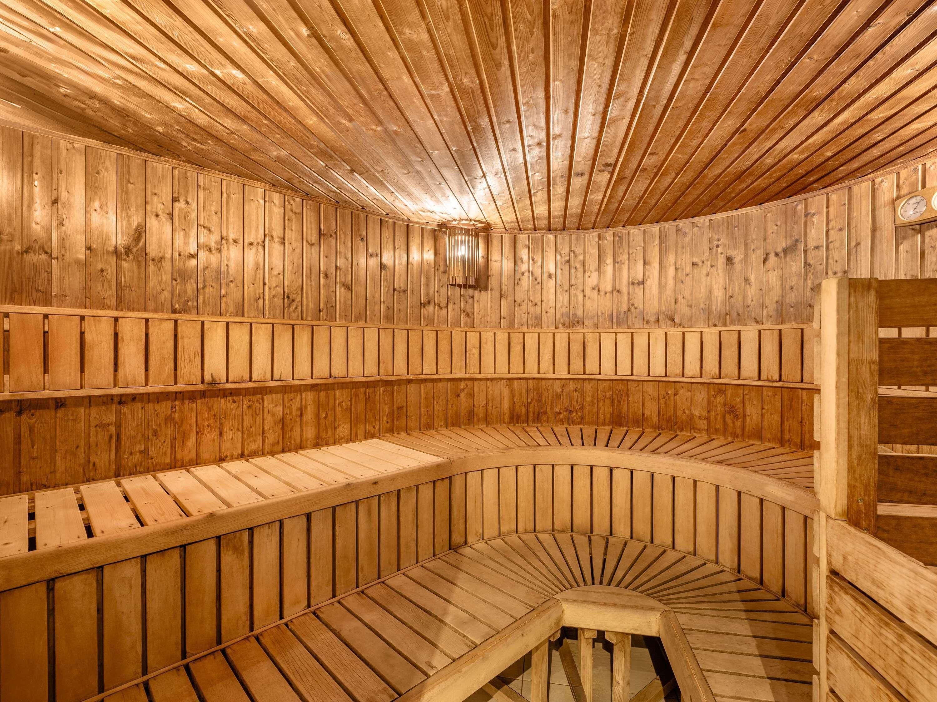 A sauna with wooden walls and benches arranged in a semi-circular pattern.