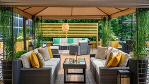 An outdoor patio with wicker furniture, a glass-top table, and a canopy.