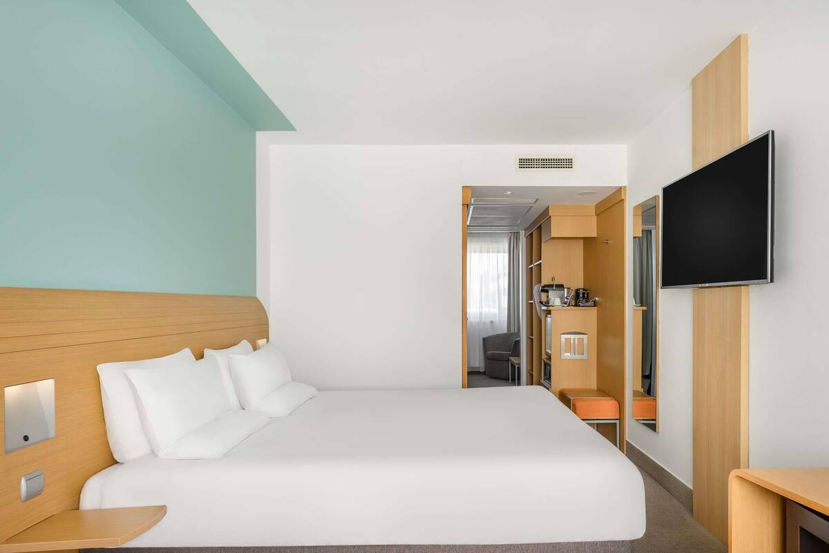 A hotel room with a bed, a TV, a desk, and a wardrobe.