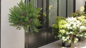 A building facade with a large window, a wall-mounted light fixture, and potted plants. - My Home in Paris Hotel (Paris)