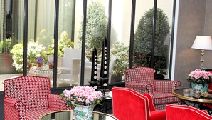 A hotel room with a large window, wicker furniture, and a table with a vase of flowers. - My Home in Paris Hotel (Paris)