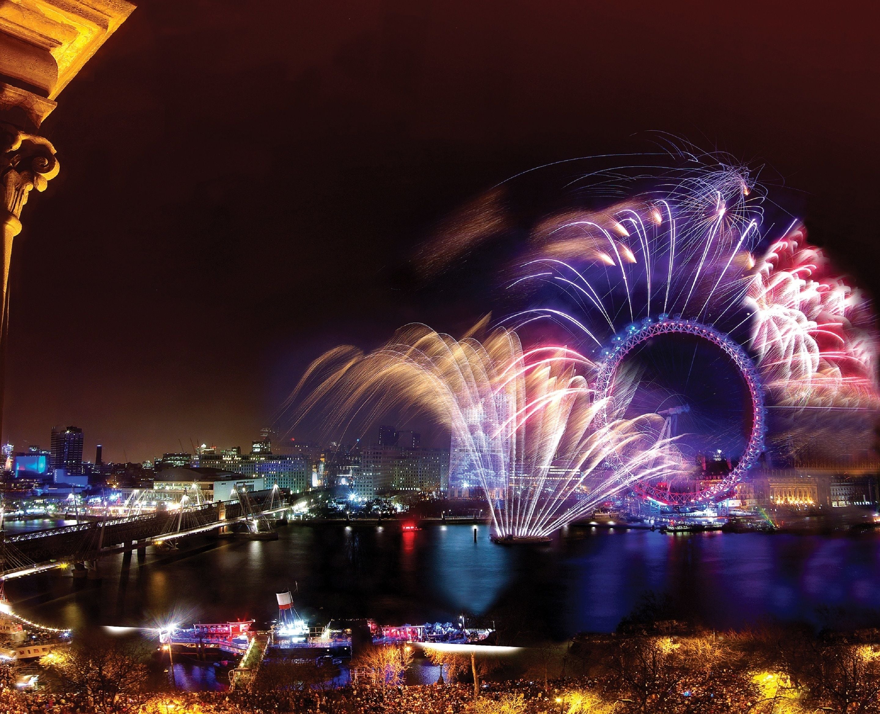 A nighttime cityscape with a prominent Ferris wheel and fireworks display.