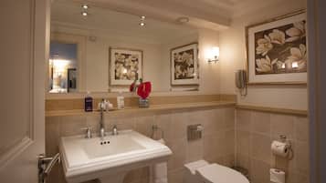 Un bagno con lavandino, WC e un quadro con fiori.