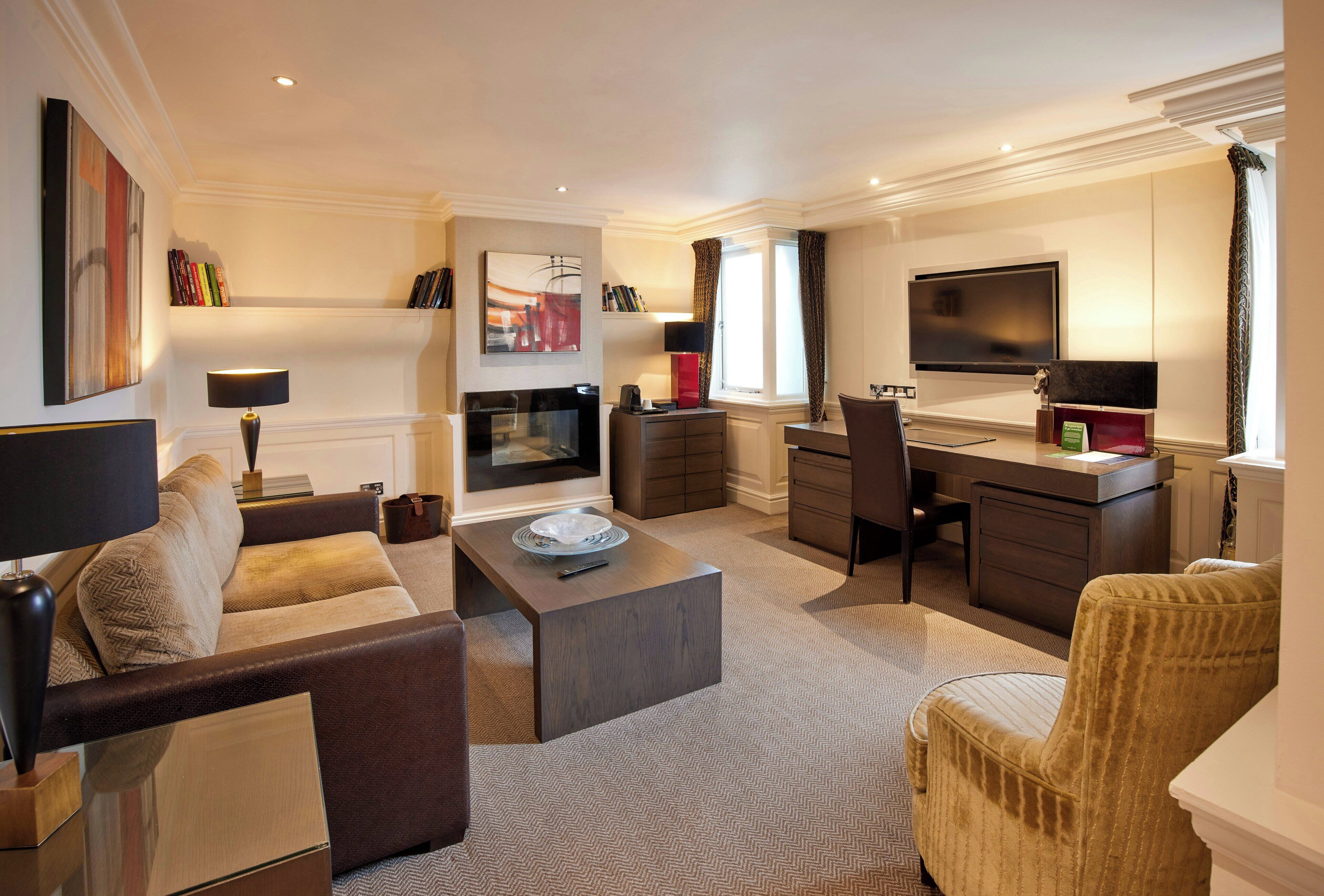 A modern living room with a sofa, coffee table, TV, and a desk with a chair.