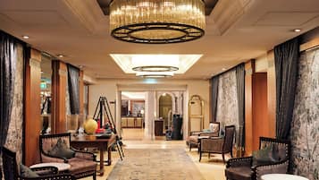 En rummelig lobby med en imponerende lysekrone, komfortable siddepladser og et klassisk design.
