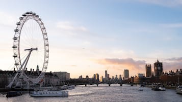 A river with boats and a large Ferris wheel in the background.