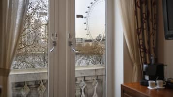 A room with a view of a Ferris wheel, a coffee machine, and a table with two cups.