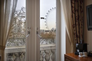 A room with a view of a Ferris wheel, a coffee machine, and a table with two cups.