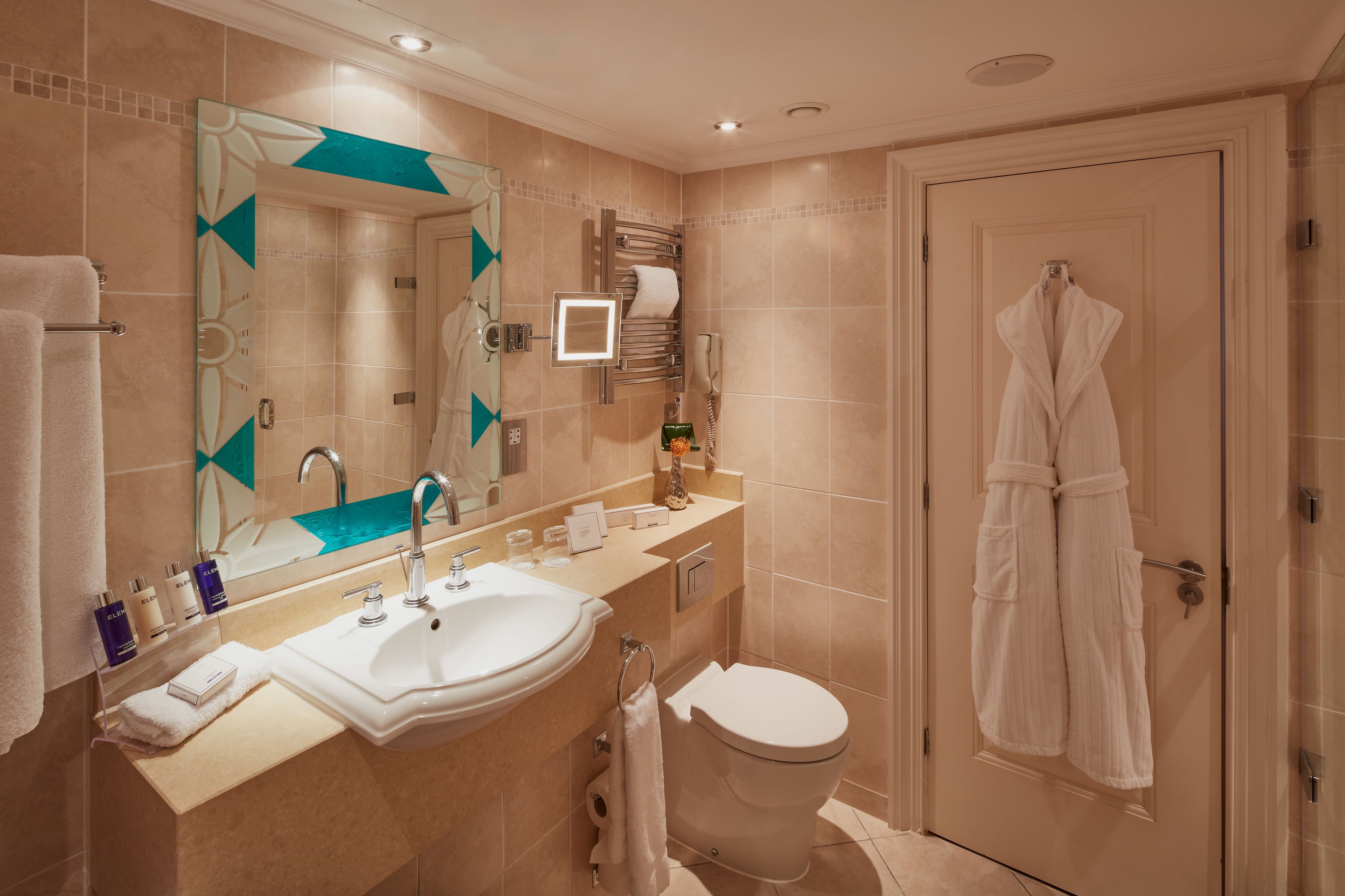 A modern bathroom with a sink, mirror, and toilet.