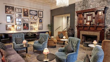 A spacious lounge with comfortable seating, a fireplace, and a wall adorned with framed pictures.