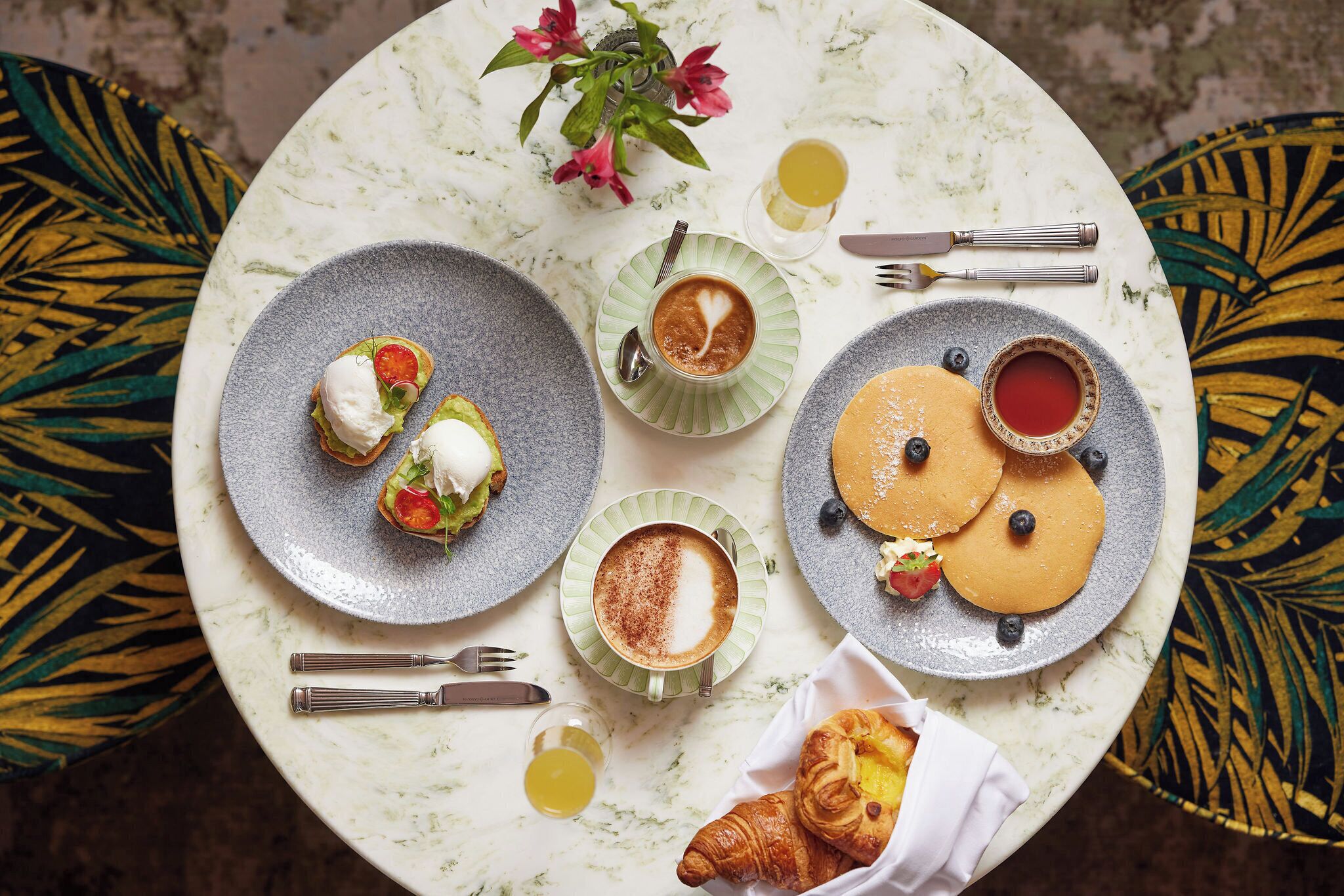 Una mesa con platos de comida, un croissant y una taza de café.