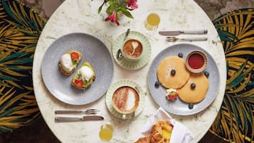 Una mesa con platos de comida, un croissant y una taza de café.