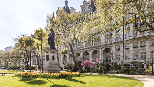 A park with a statue, well-maintained grass, and flowering plants. - The Royal Horseguards, London (London)