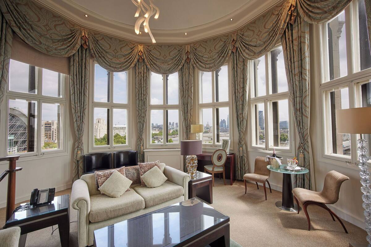 A spacious room with a large window, a sofa, a coffee table, and a dining area.