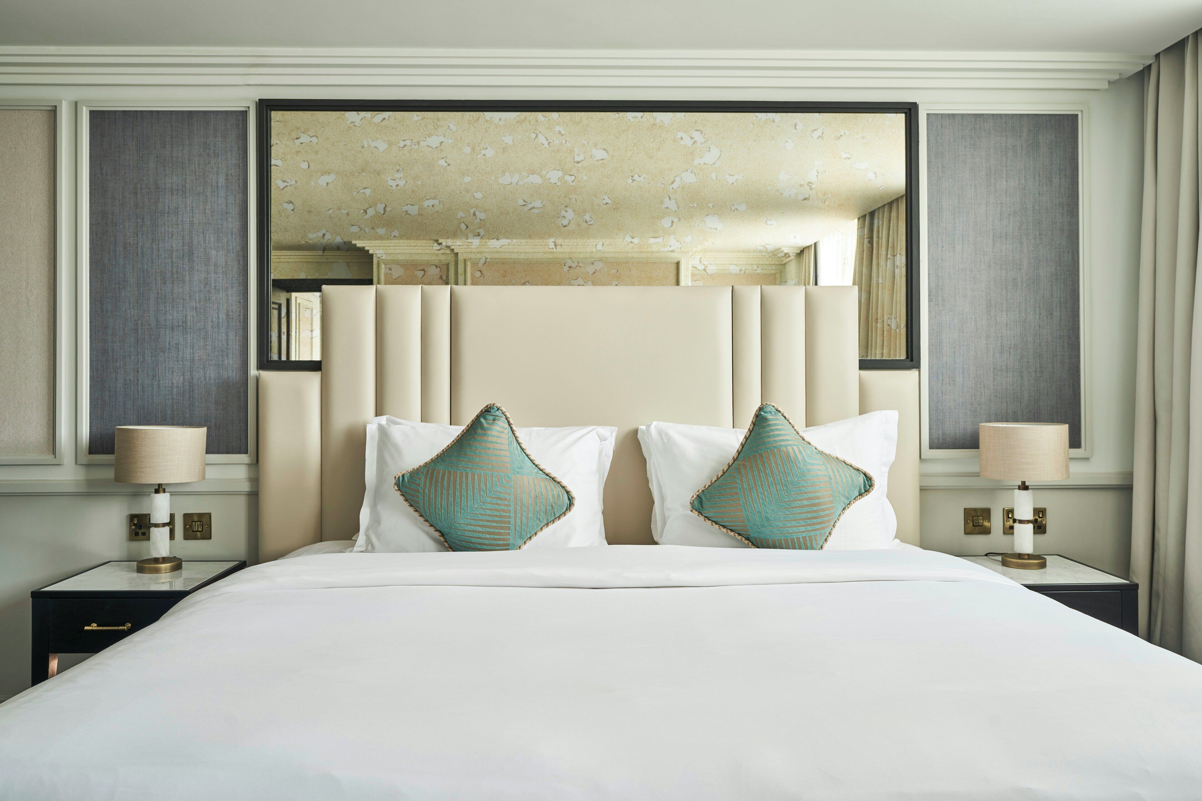 A hotel room with a large bed, two nightstands, and a mirror above the bed.