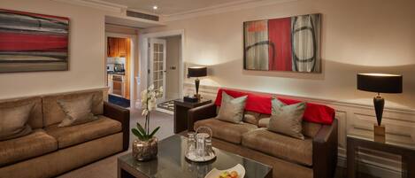 A modern living room with two sofas, a coffee table with fruit, and abstract wall art.