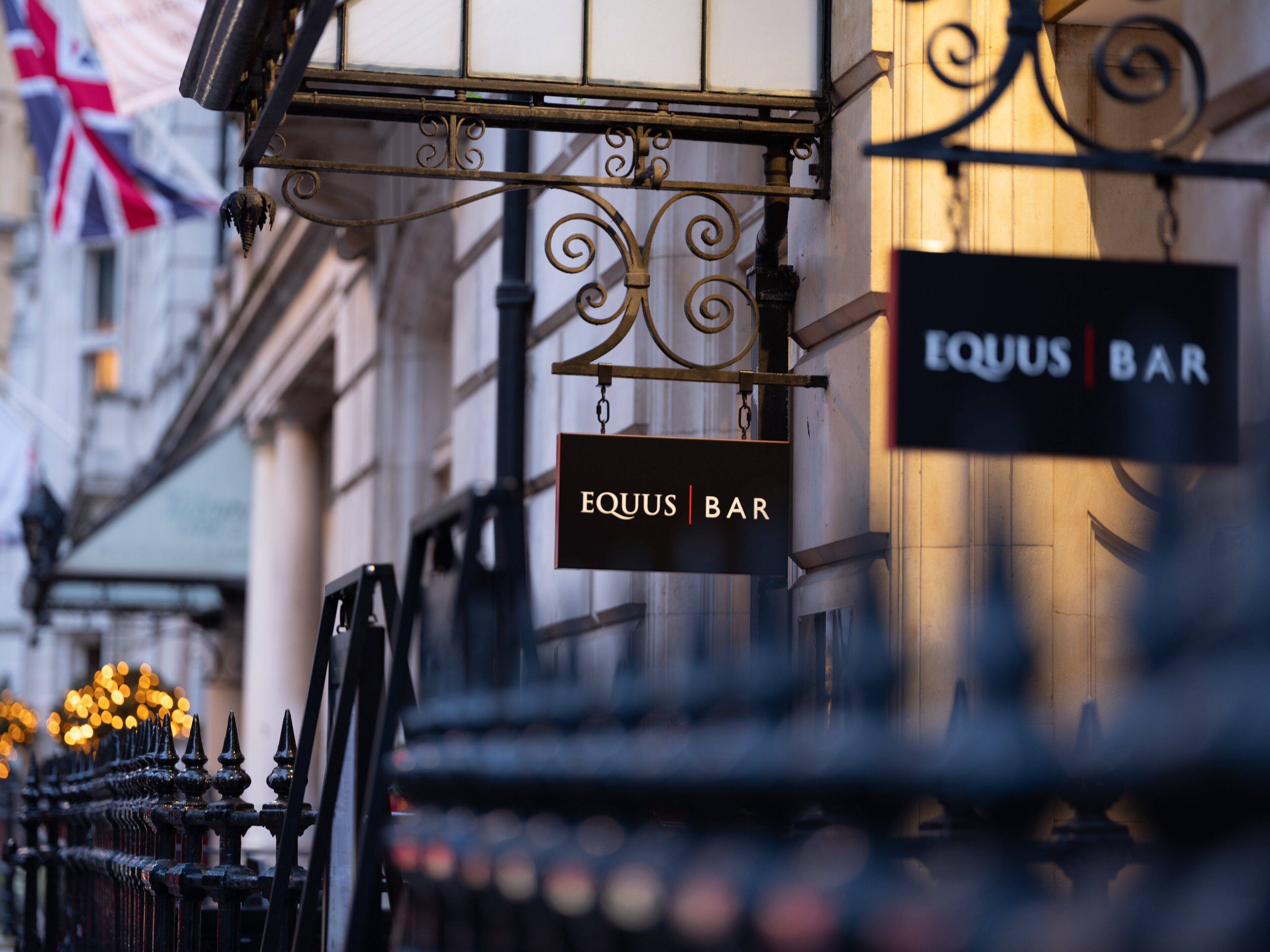 A bar sign with the name 'Equus Bar' hanging from a metal structure.