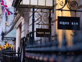Ein Bartischschild mit der Aufschrift 'Equus Bar', das an einer Metallkonstruktion hängt.