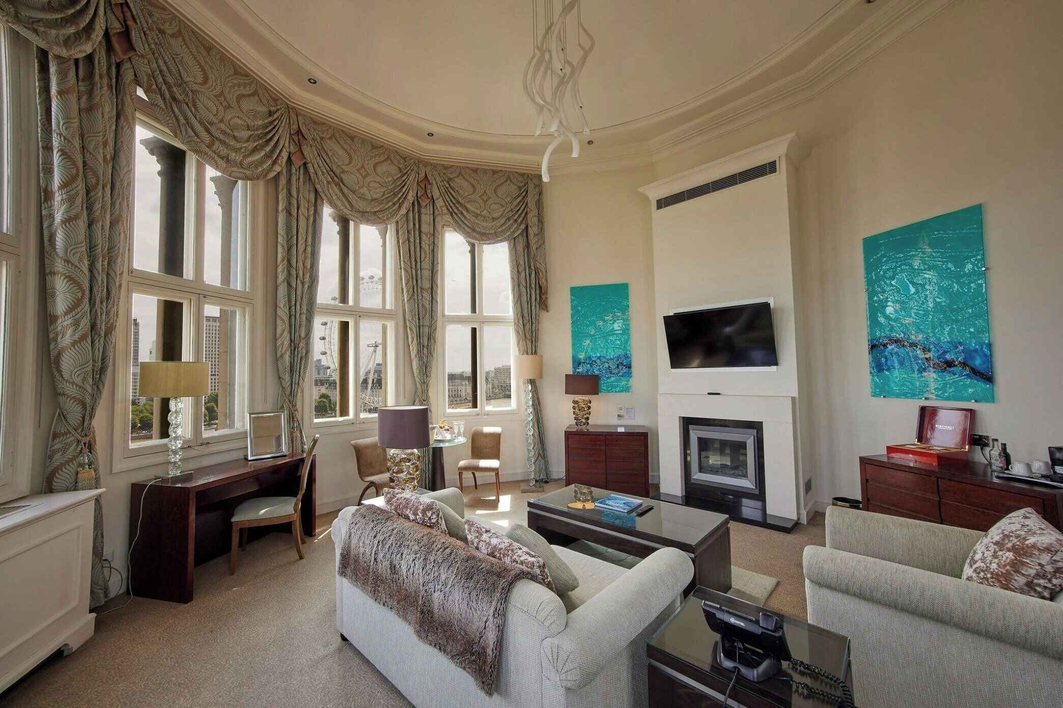 A spacious living room with a fireplace, a television, and a large window with curtains.
