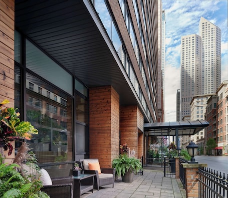 A hotel with a modern exterior, large windows, and a covered outdoor seating area with plants and furniture.. Sonesta ES Suites Chicago Downtown Magnificent Mile - Medical