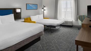 A hotel room with two beds, a desk, a chair, a TV, a window with curtains, and a wall-mounted picture.