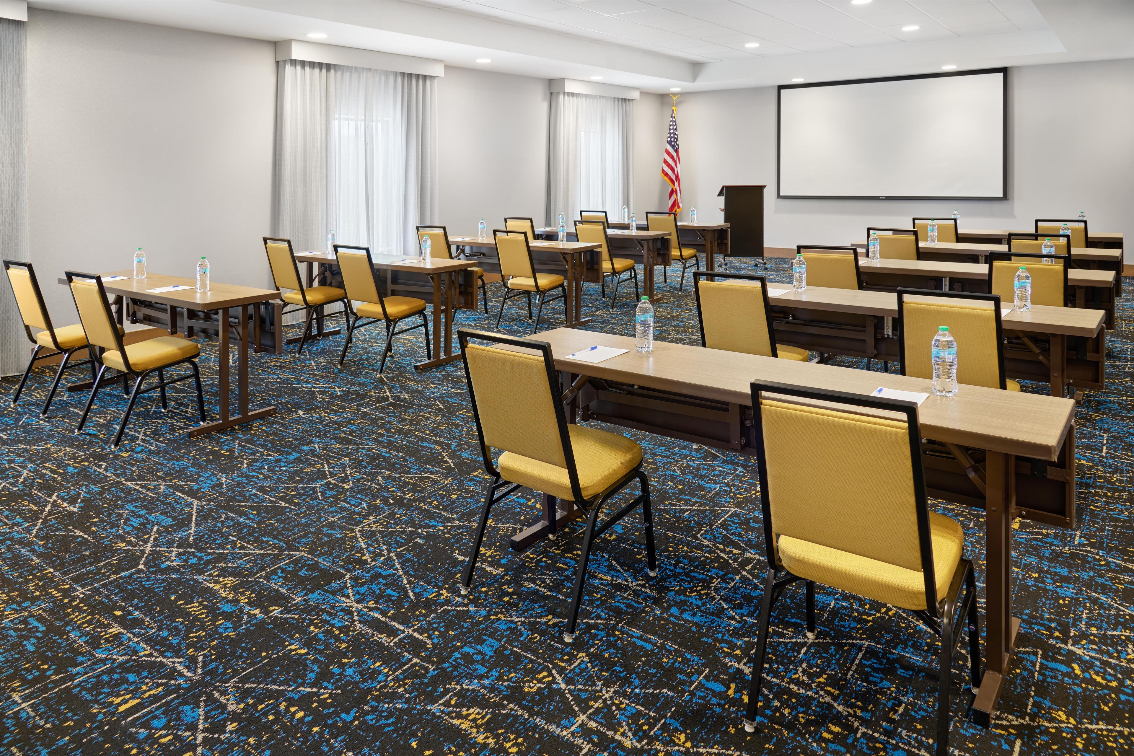 Un salón de conferencias con mesas, sillas y una bandera estadounidense.