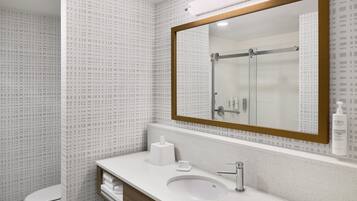 A bathroom with a white sink, a mirror with a wooden frame, a toilet, and a shower area.