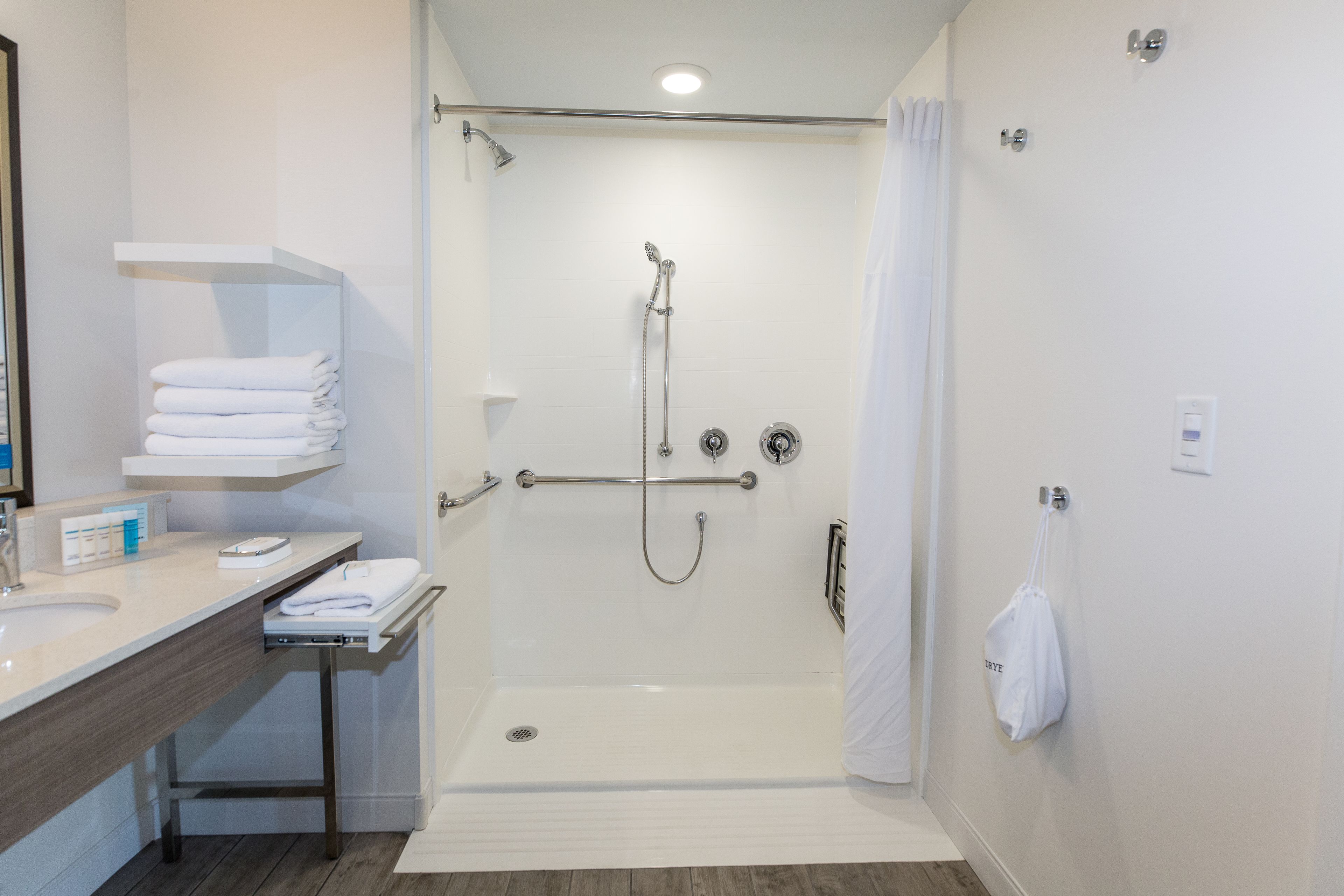 Et moderne badeværelse med brusebad, et spejlskab med vask og håndklædetørre samt toilet.