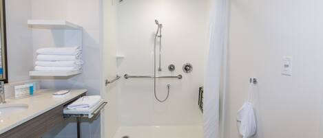 A modern bathroom with a walk-in shower, a vanity with a sink and towel rack, and a toilet.