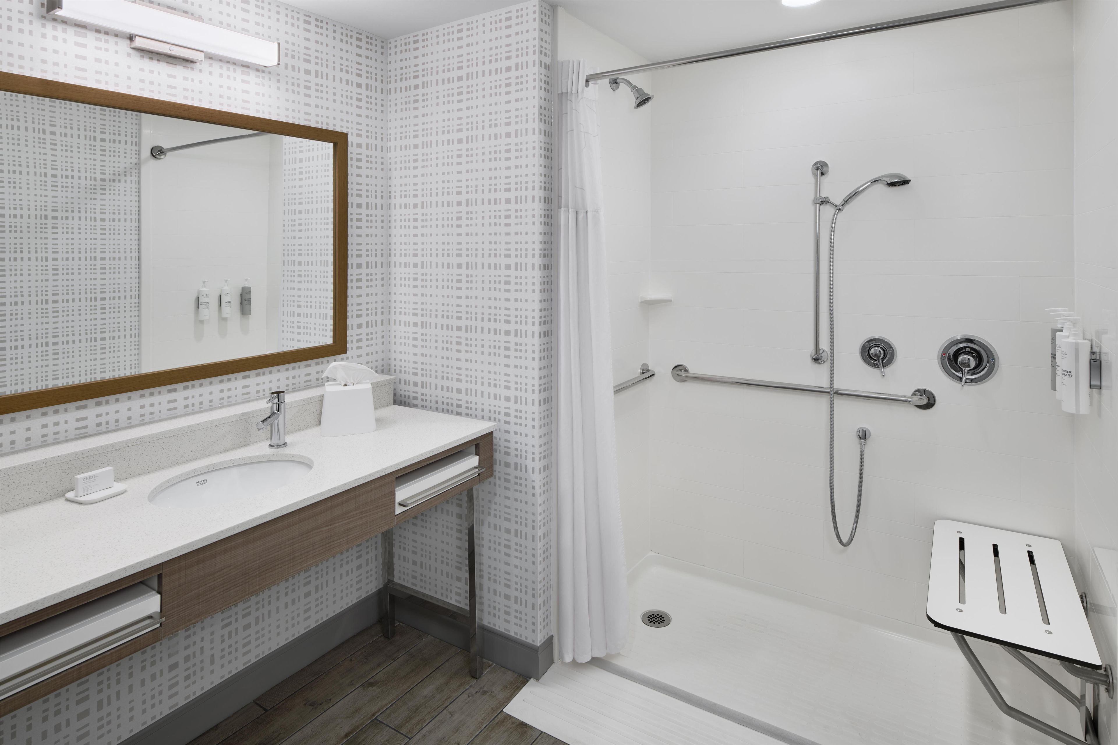 A modern bathroom with a shower, a sink, and a mirror.