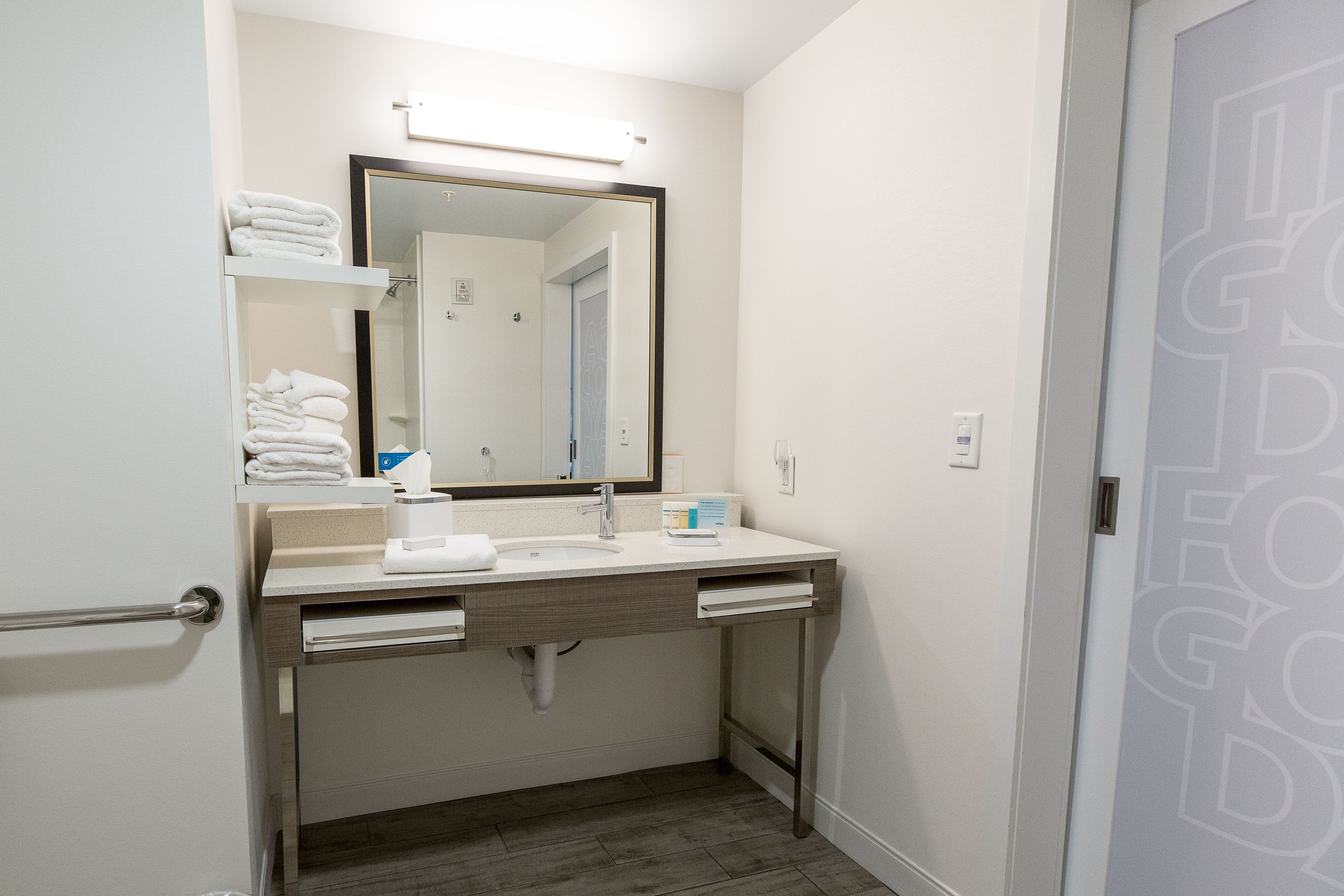 A modern bathroom with a white sink, a mirror, and a towel rack.