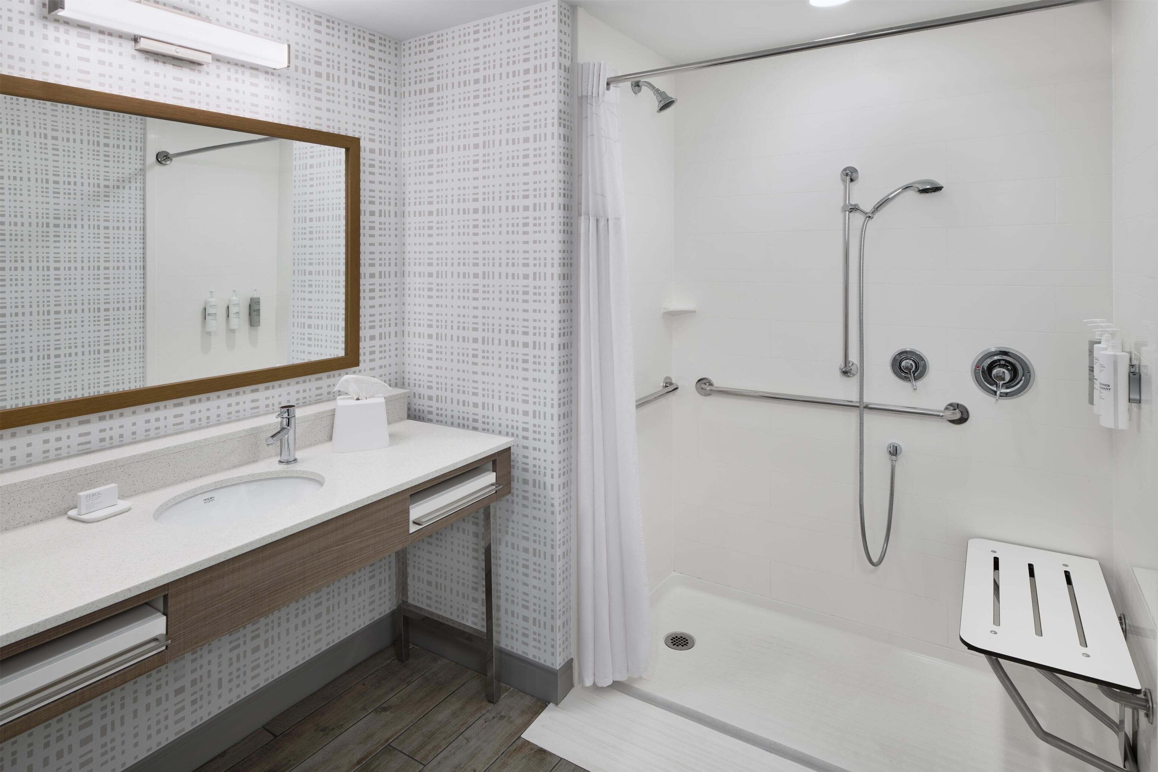 Een moderne badkamer met een douche, wastafel en spiegel.