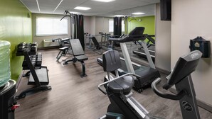 A gym with treadmills, weight machines, and dumbbells.