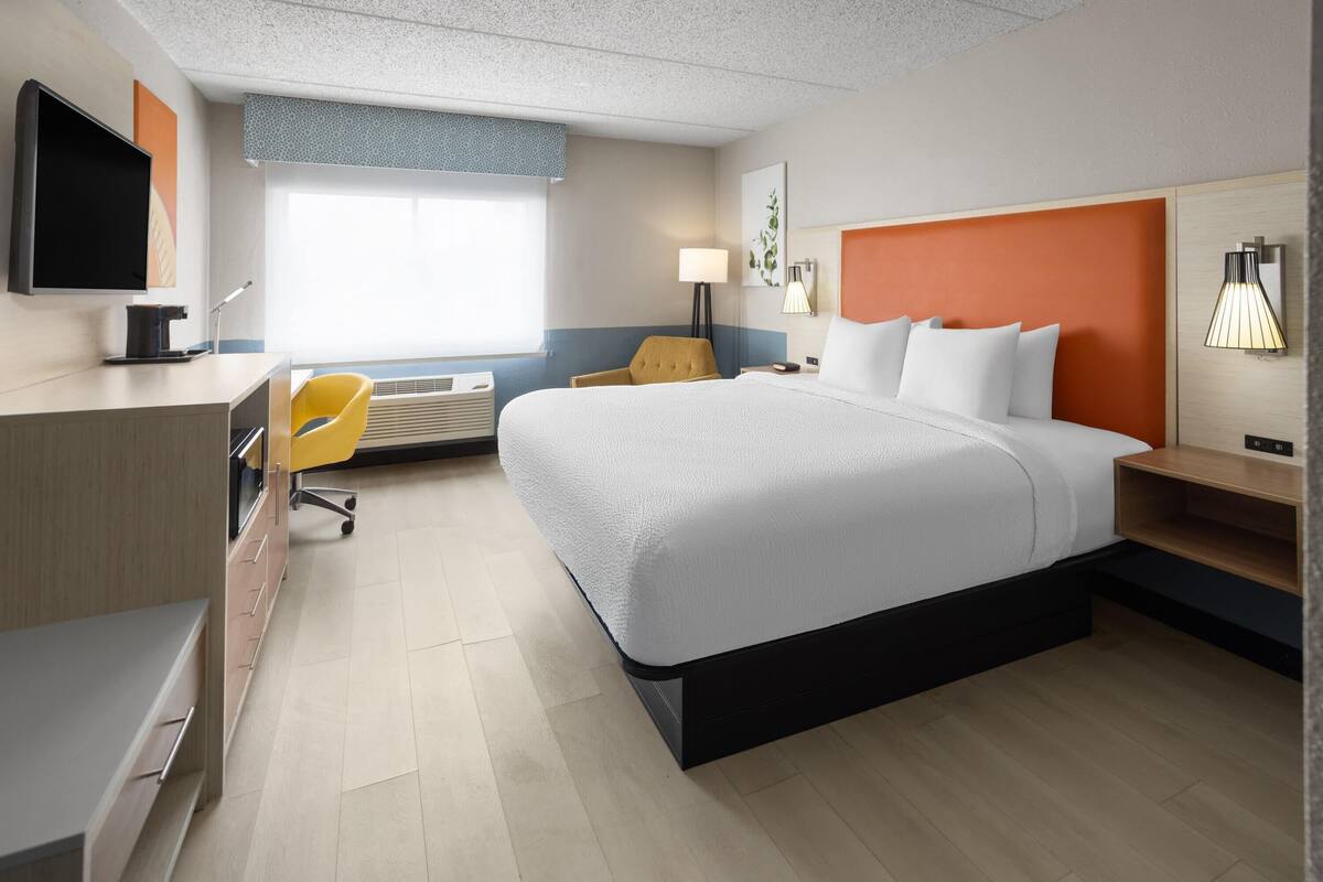 Une chambre d’hôtel équipée d’un lit, d’un bureau, d’une chaise et d’un téléviseur.