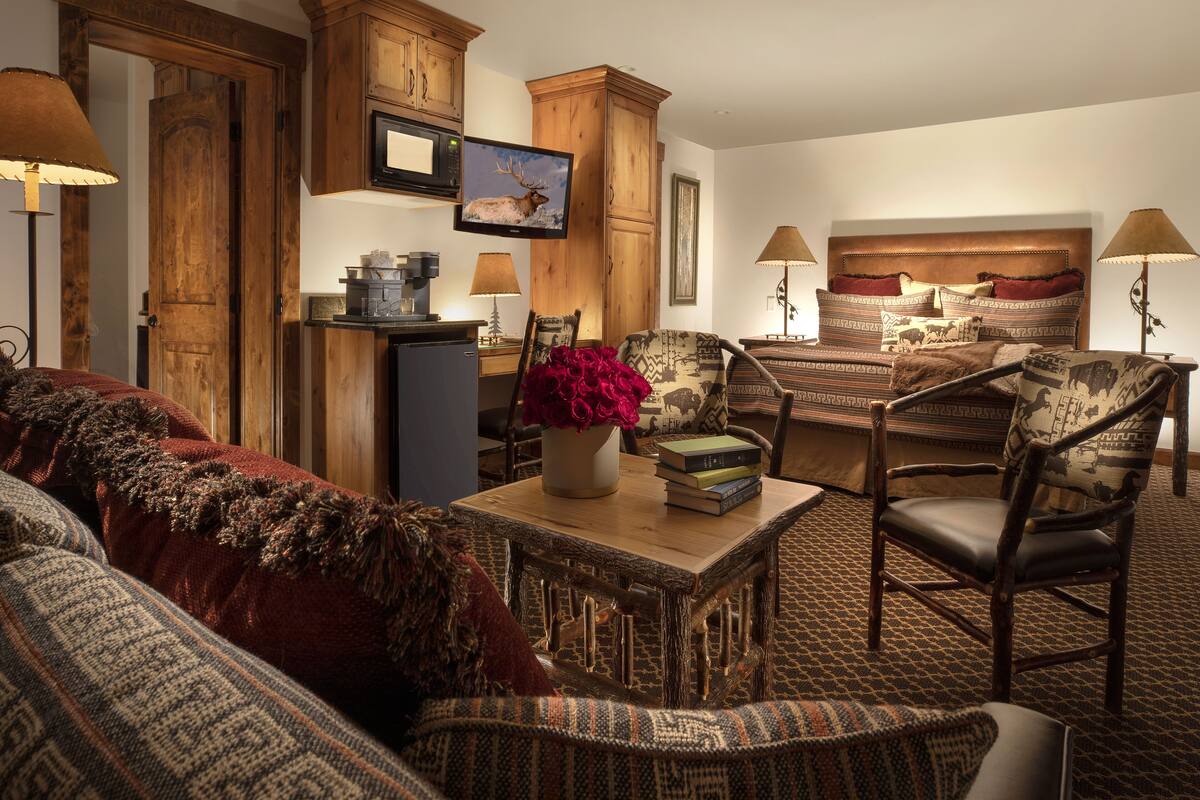 A cozy room with a bed, a wooden cabinet, a television, and a small table with a vase and books.