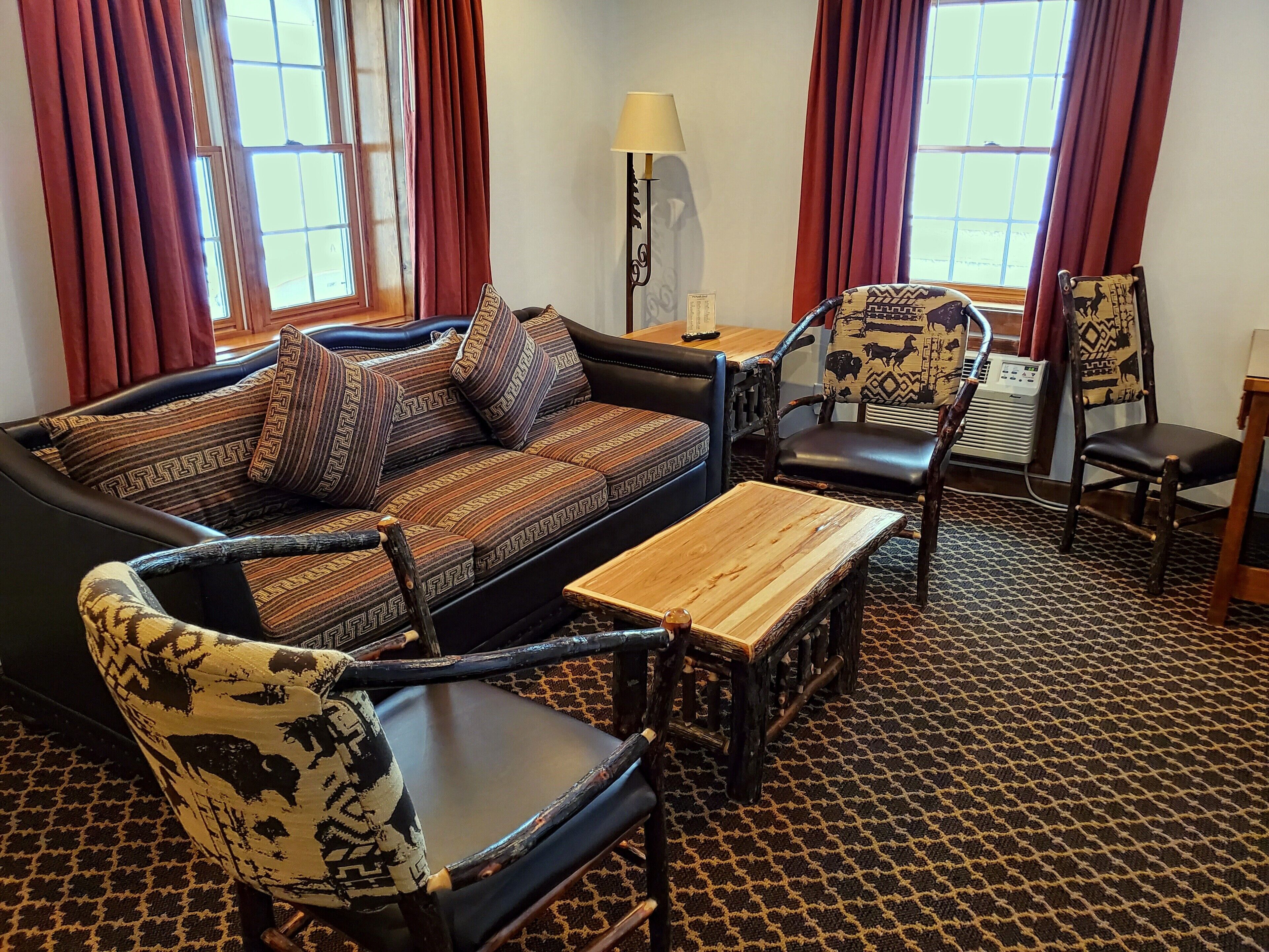A living room with a sofa, two patterned armchairs, a wooden coffee table, and a patterned carpet.