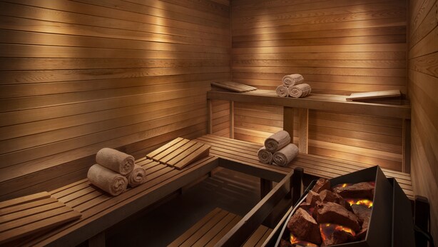 A sauna with wooden benches, towels, and a visible firebox.