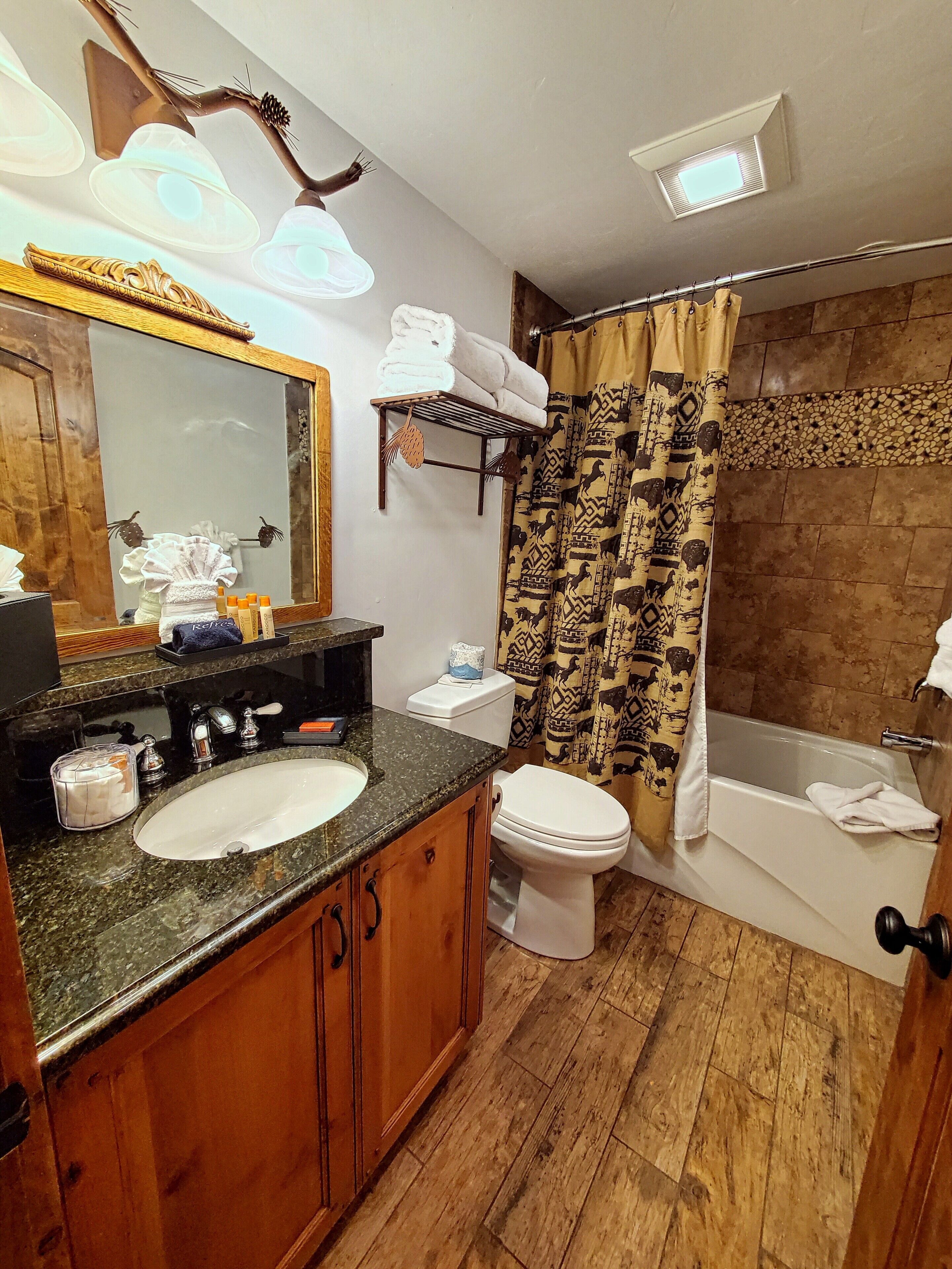 Un baño con un tocador de madera, un lavabo, un inodoro y una bañera.