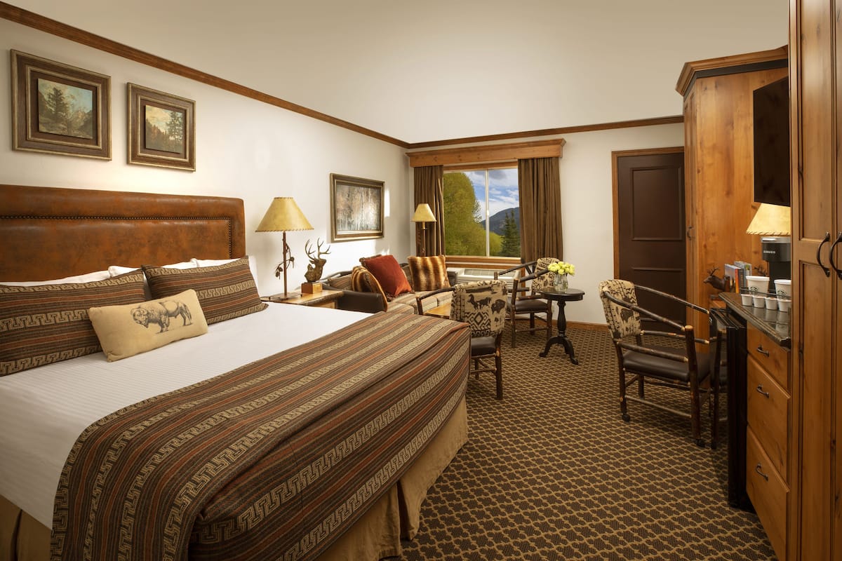 A hotel room with a large bed, a desk, a chair, and a wardrobe.