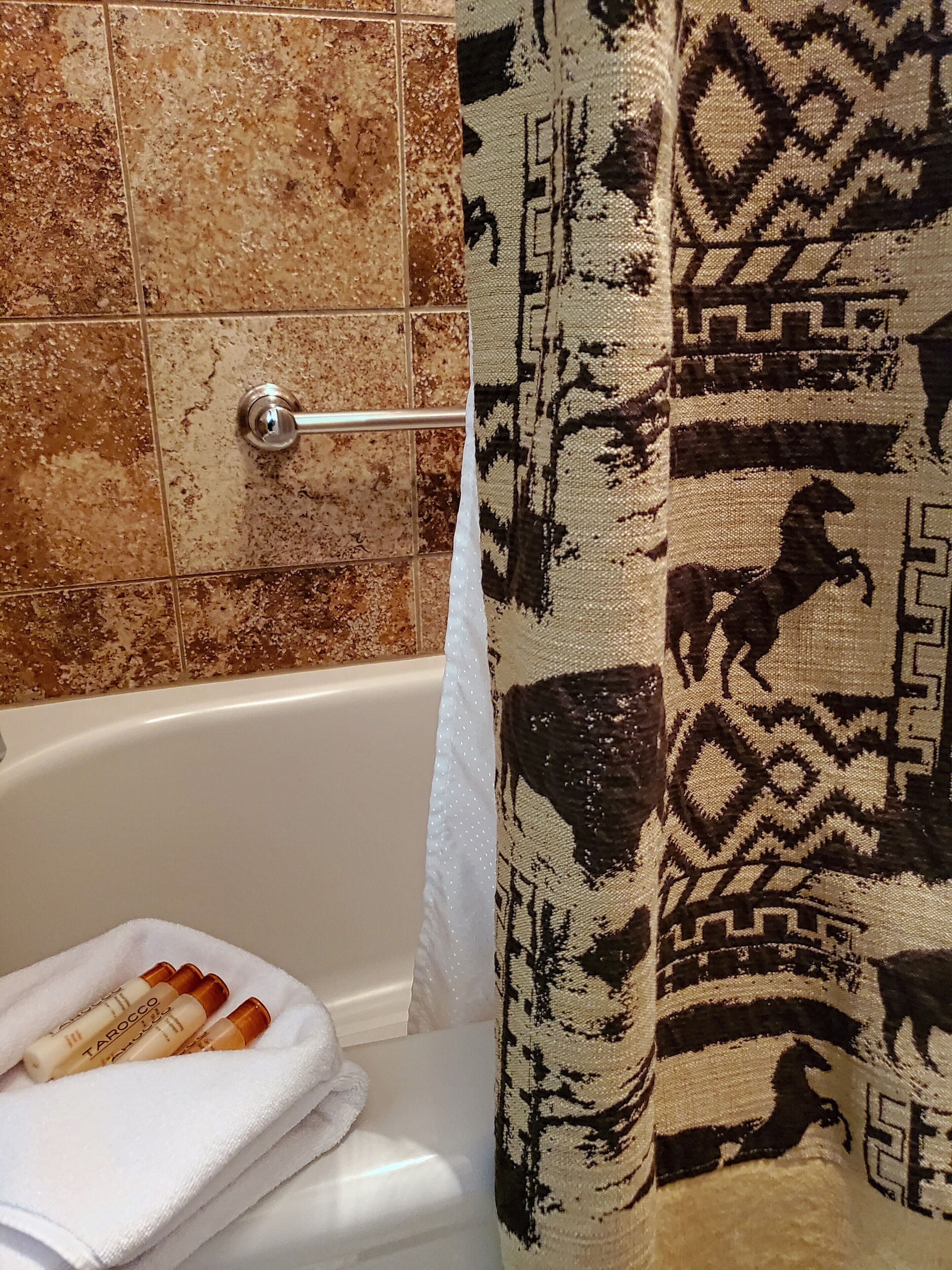 A bathroom with a bathtub, a towel, and toiletries.