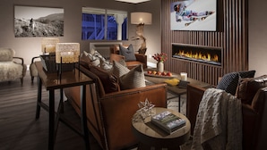 A modern living room with a fireplace, leather sofas, and a television.