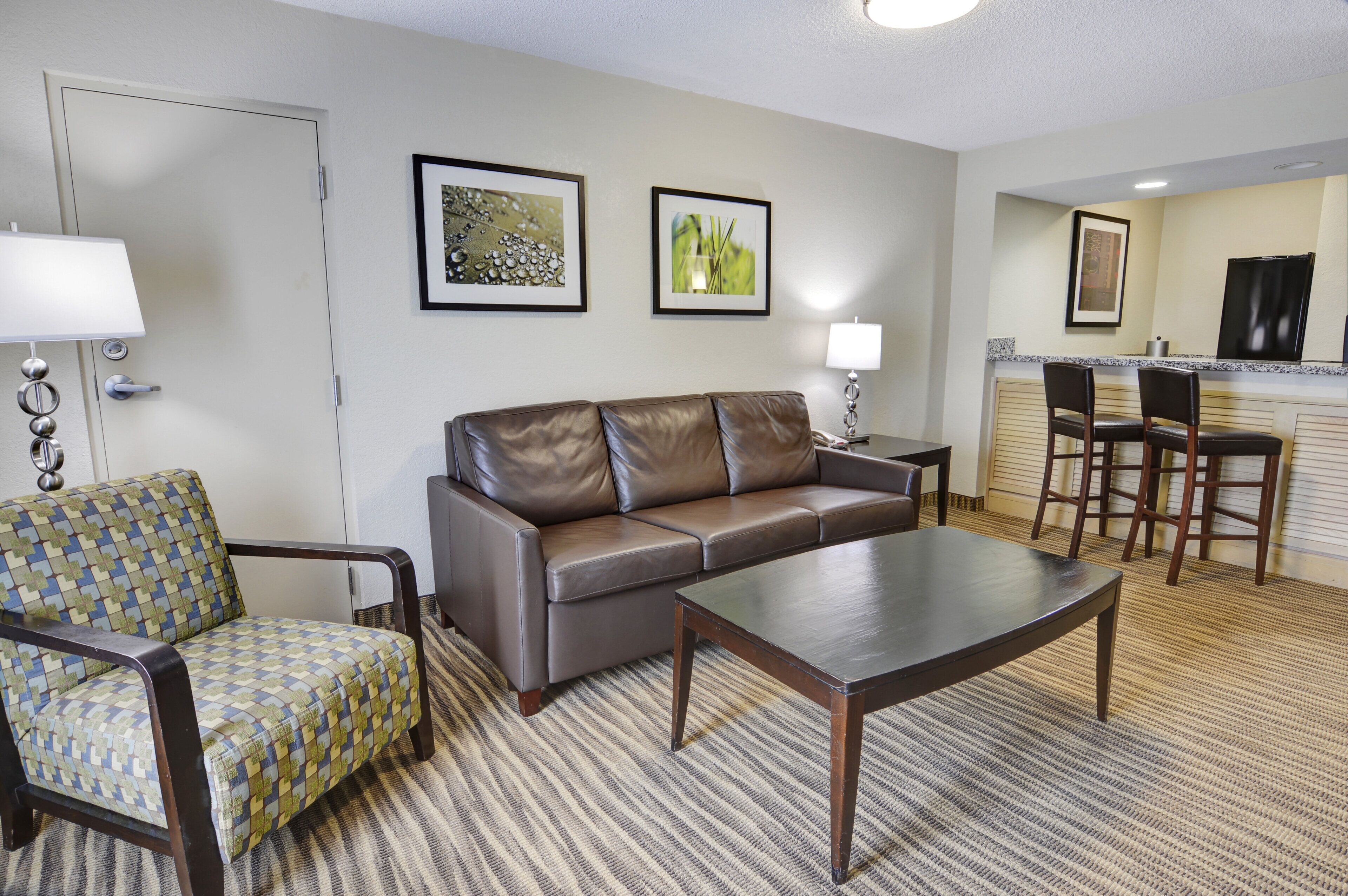Une chambre d’hôtel équipée d’un canapé, d’un fauteuil, d’une table basse et d’un petit coin repas avec une table et des chaises.