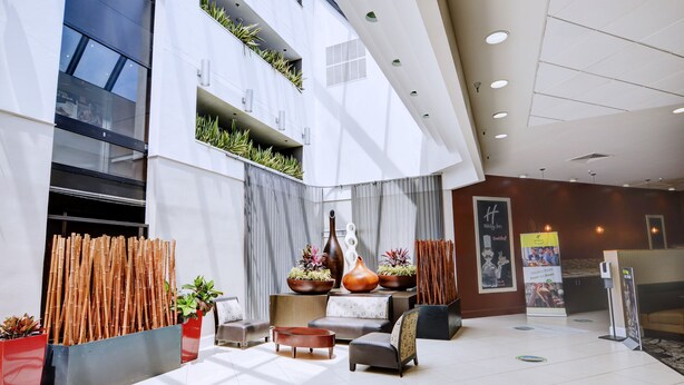A modern lobby with a high ceiling, large windows, and a seating area with sofas and a coffee table. - Holiday Inn St Petersburg N - Clearwater by IHG (Clearwater)