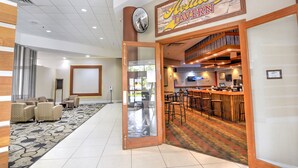 A hotel lobby with a bar area, seating, and a large mirror. - Holiday Inn St Petersburg N - Clearwater by IHG (Clearwater)