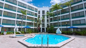 A hotel with a central swimming pool, multiple balconies, and outdoor seating areas. - Holiday Inn St Petersburg N - Clearwater by IHG (Clearwater)