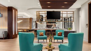 Un vestíbulo con sillones azul turquesa, una zona de bar y un televisor de pantalla plana grande.
